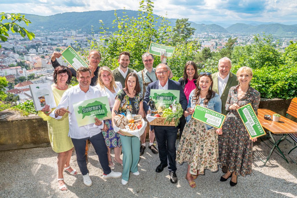 Eine Gruppe Menschen posiert mit dem Logo vom Kochbuch Steiermark genißen