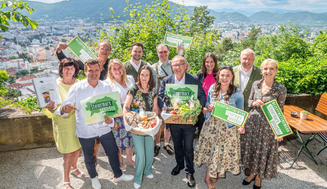 Eine Gruppe Menschen posiert mit dem Logo vom Kochbuch Steiermark genißen